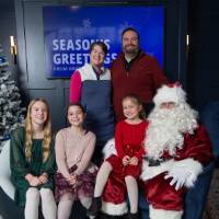 Parents with three girls smile with Santa